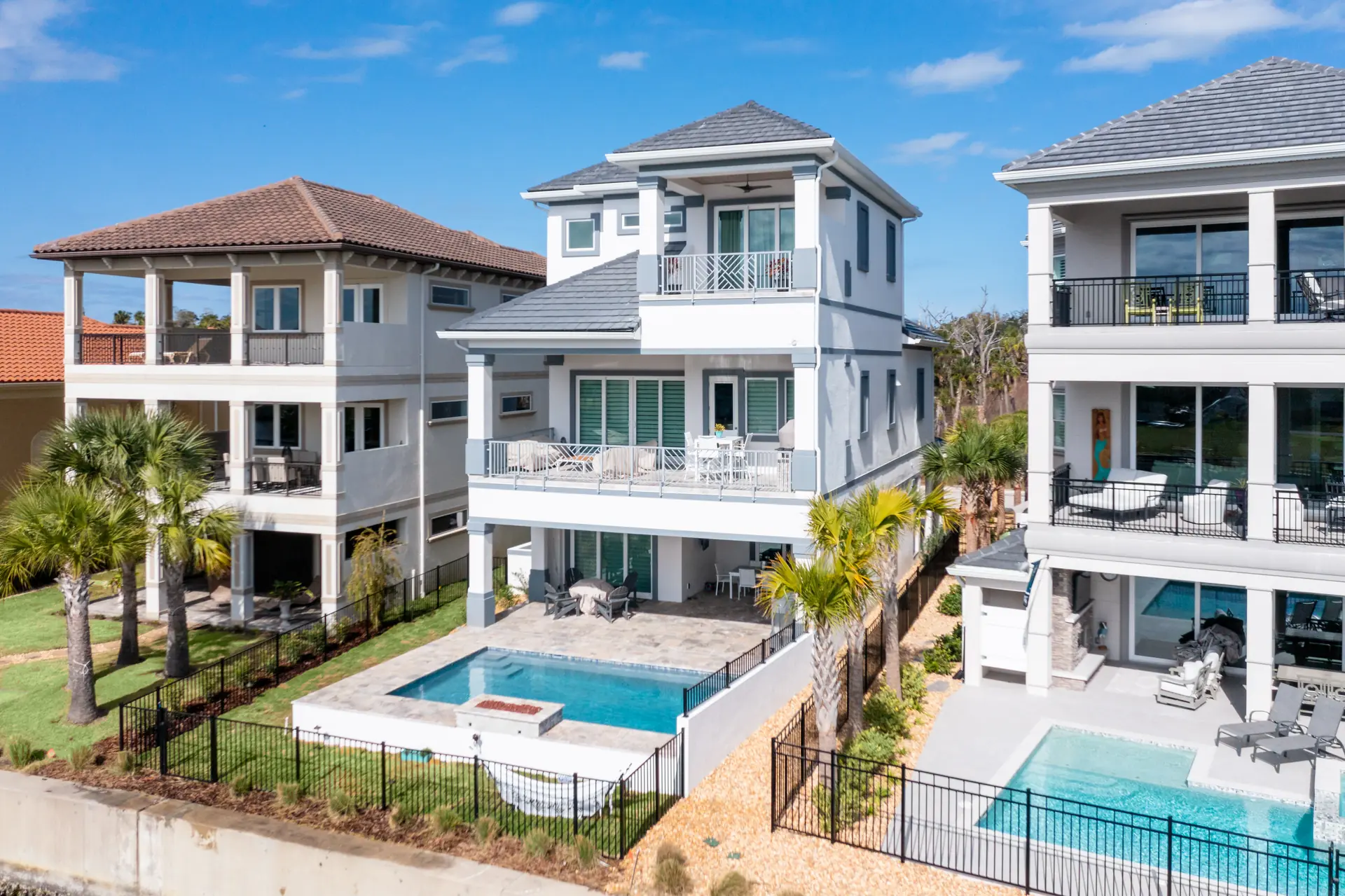 Aerial view of a waterfront residence, pool, and neighboring homes