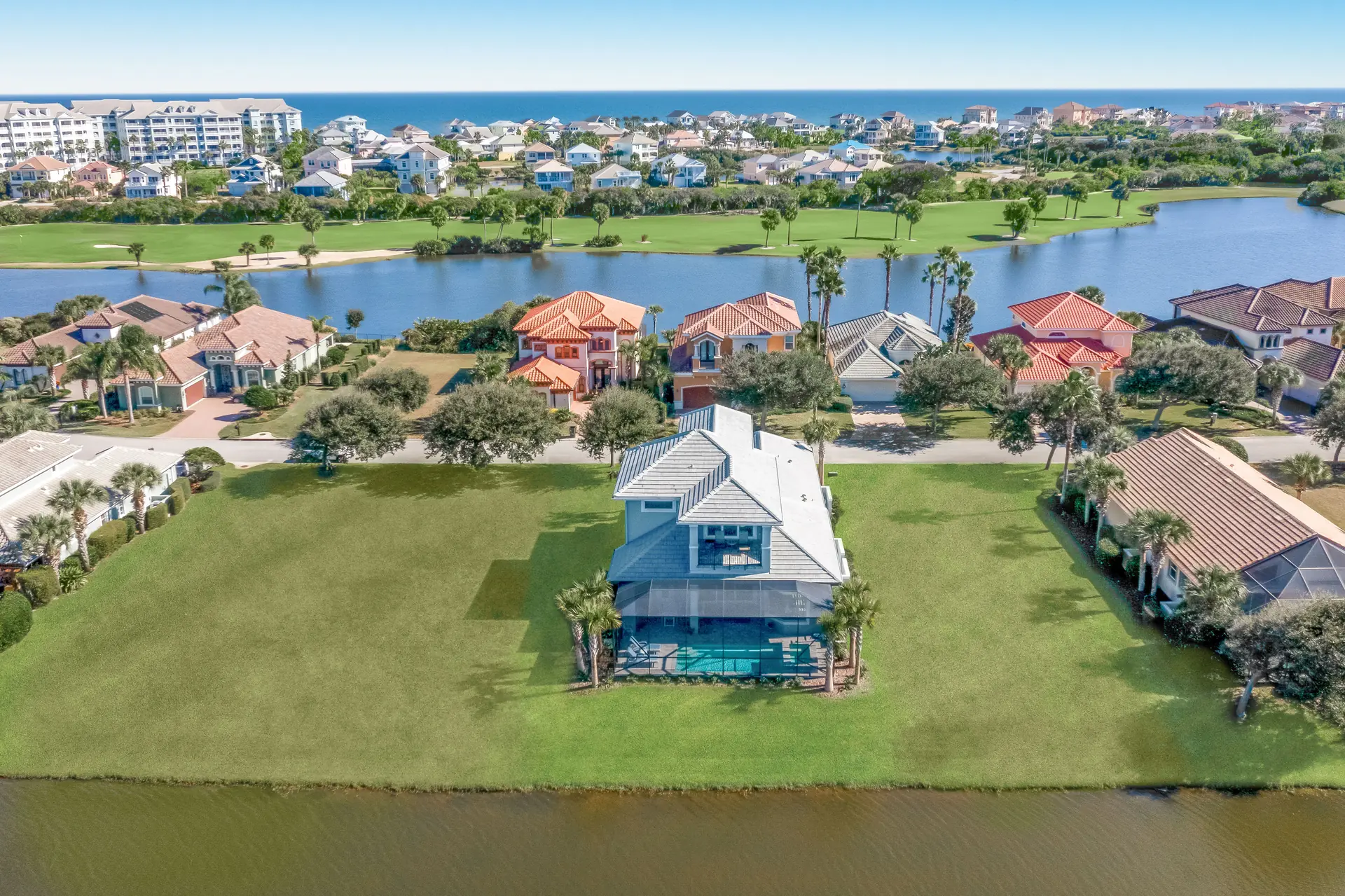 High aerial view of a lakefront custom home in a golf community