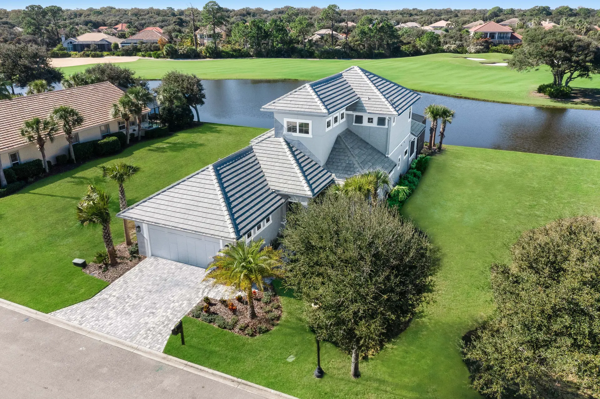 Aerial view of a custom home beside a lake and golf course