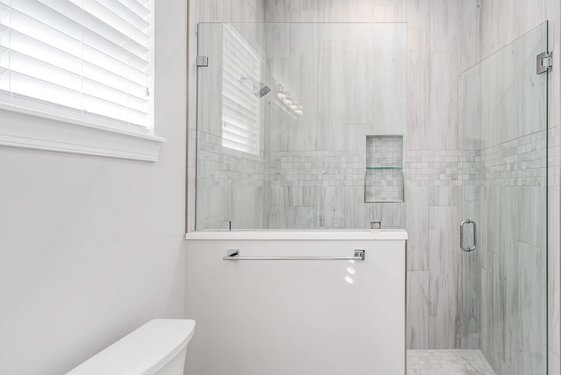 Guest bathroom with glass shower and softly textured tile