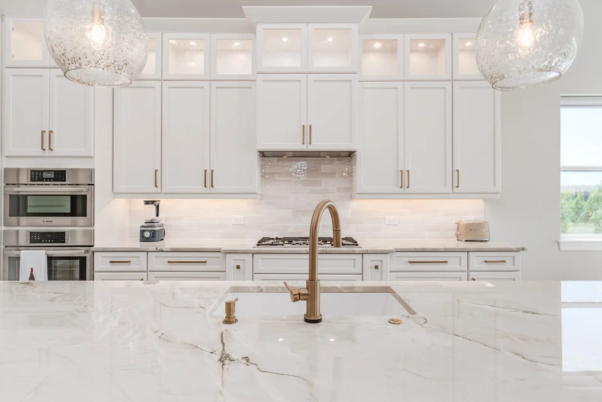 Custom kitchen island with waterfall countertop and pendant lighting